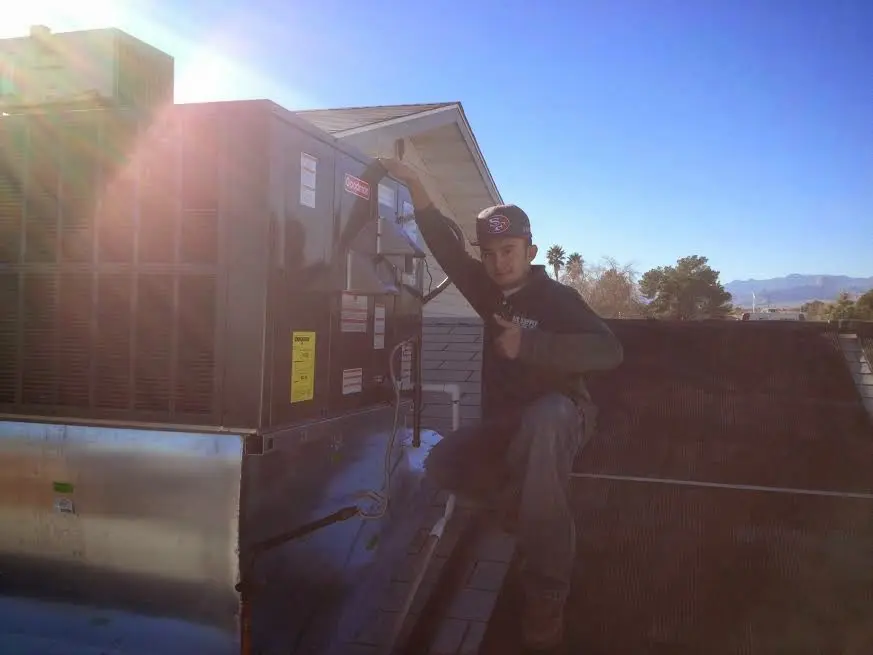 HVAC technician performing Air Duct Cleaning on a rooftop unit in East Bakersfield